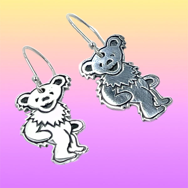 Silver bear-shaped earrings on a gradient background