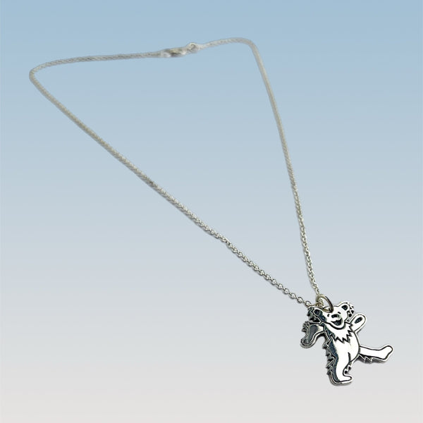 Silver necklace with a dancing bear pendant on a light blue background