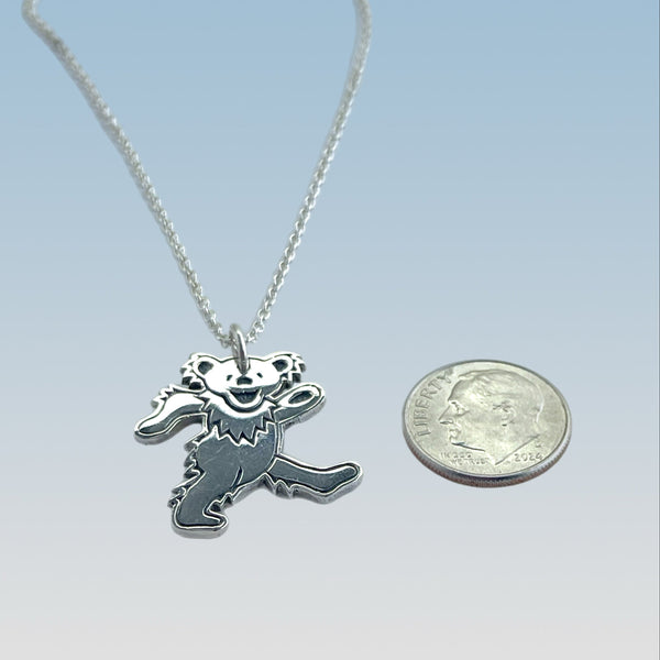 Silver pendant necklace next to a quarter on a light blue background