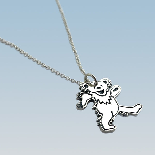 Silver dancing bear pendant on a chain against a light blue background