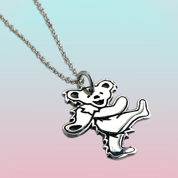 Silver pendant of a bear on a chain against a gradient background