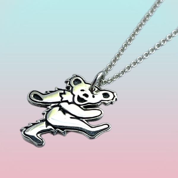Silver pendant shaped like a bear on a chain against a gradient background
